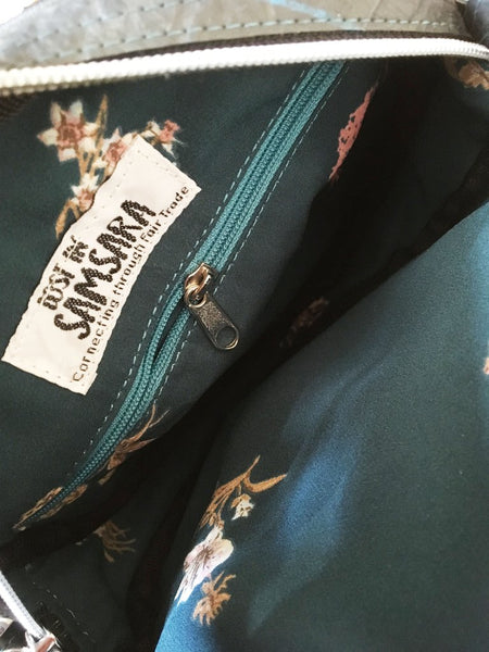 Inside view of the fair trade recycled tyre bag showing the fabric lining inside the bag. This is dark blue with a yellow flower pattern and a contrasting light blue inside zip.