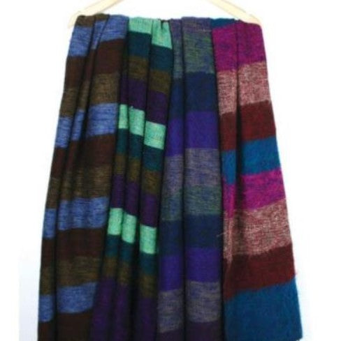4 fair trade recycled wool shawls hanging from a wooden coat hanger. They are shades of purple blue, brown and green.