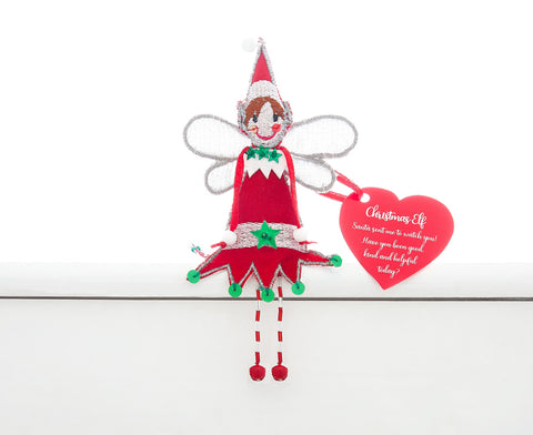 A fair trade handmade Christmas elf sitting on a white shelf. He has a red tunic with silver and green trim, silver wings and a red and silver pointy hat. There are bells on his hat and at the ends of his red and white beaded legs.