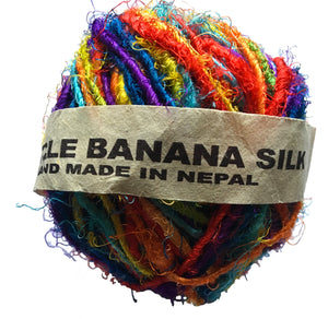A ball of fair trade recycled banana silk yarn in vibrant rainbow colours wrapped in a paper label.