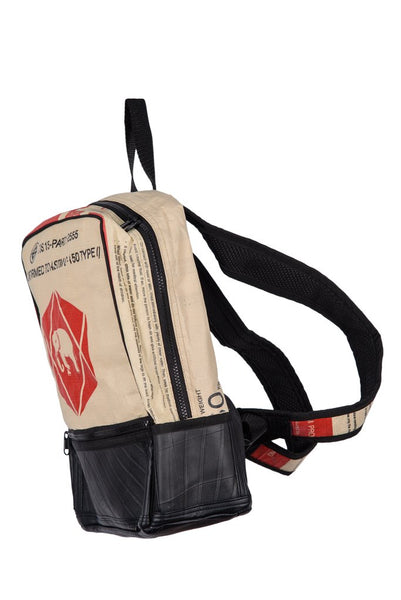Fair trade, eco friendly, vegan backpack viewed from the side. The main panel is a red and cream cement bag with an elephant logo and the bottom is black recycled tyres. There is a side zip and the rucksack straps are black on the inside and red and cream cement bag material on the outside