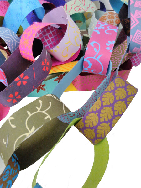 multicoloured and patterned paper chain in a pile on a white background