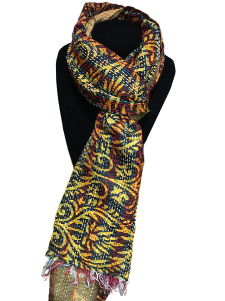 Fair trade kantha work scarf made from old saris. This scarf is displayed on a black stand and has red and blue stripes overlaid with a swirling gold pattern.