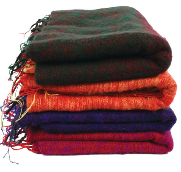 A pile of 4 fair trade recycled wool shawls. They are shades of purple blue, orange and black and all have tassels.