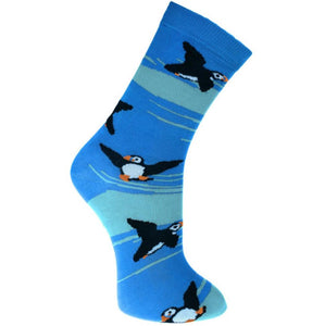 Fair trade bamboo socks with a pattern of black, white and yellow puffins on a dark and light blue sea background.